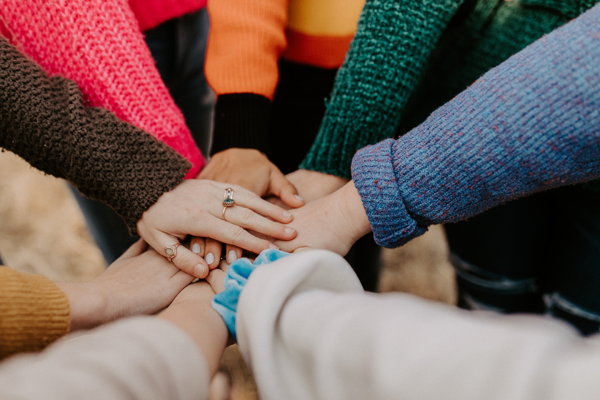 Gruppe von Frauen, die sich in der Mitte eines Kreises die Hände reichen.