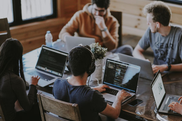 Menschen sitzen an einem Tisch und arbeiten mit Computern.