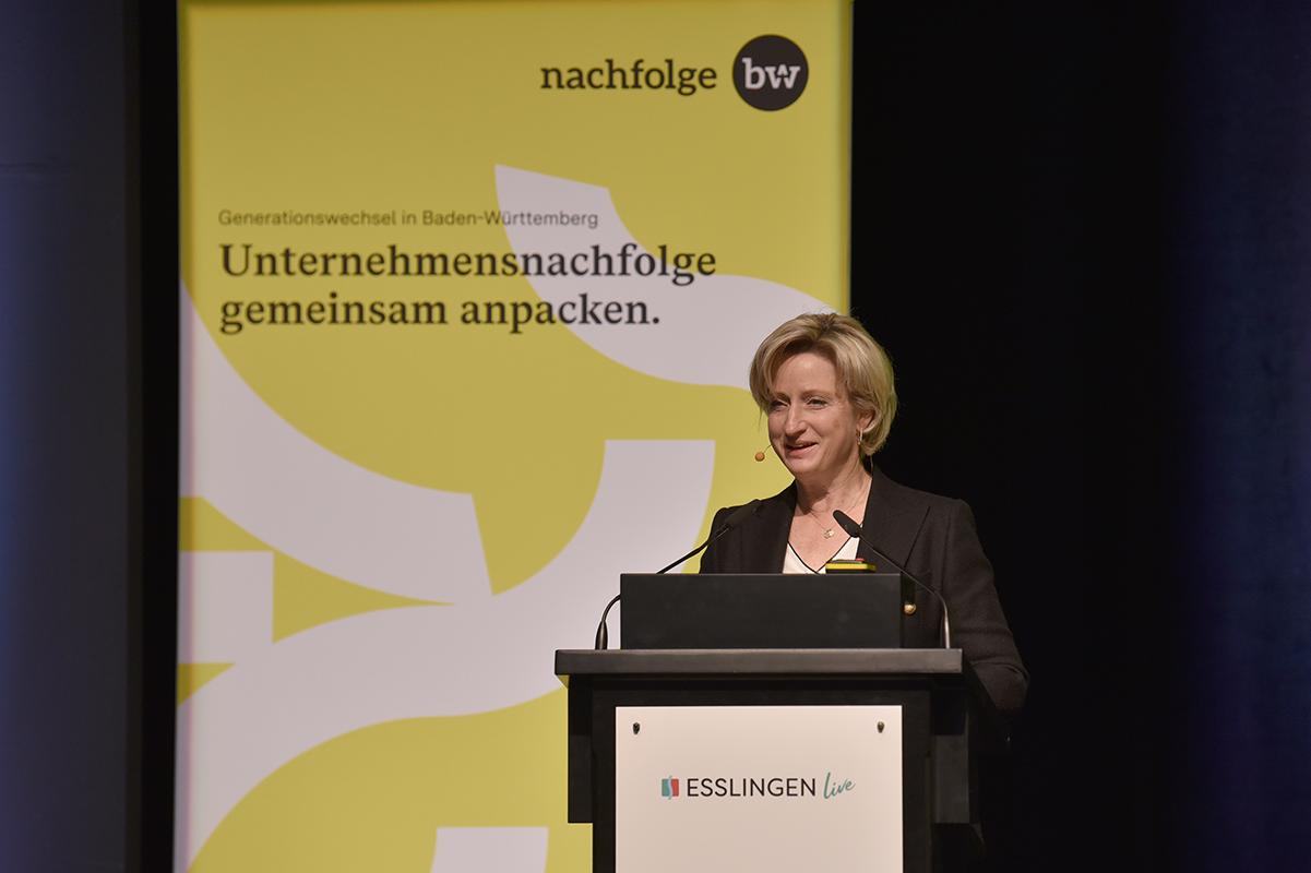 Wirtschaftsministerin Dr. Nicole Hoffmeister-Kraut spricht an einem Pult im Rahmen der Veranstaltung "Generationswechsel in Baden-Württemberg: Unternehmensnachfolge gemeinsam anpacken".