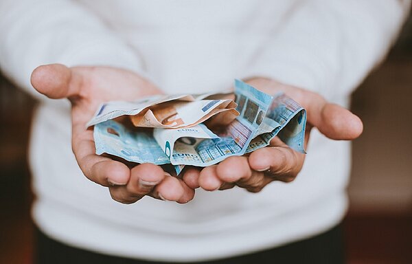 Eine Person hält mehrere Euro-Geldscheine in ihren Handflächen.